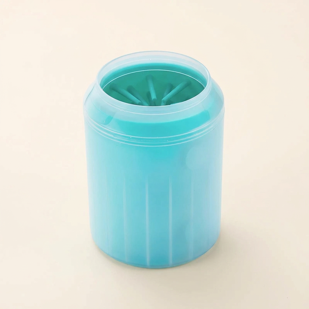 Turquoise dog paw cleaning cup with flexible inner bristles on a cream background