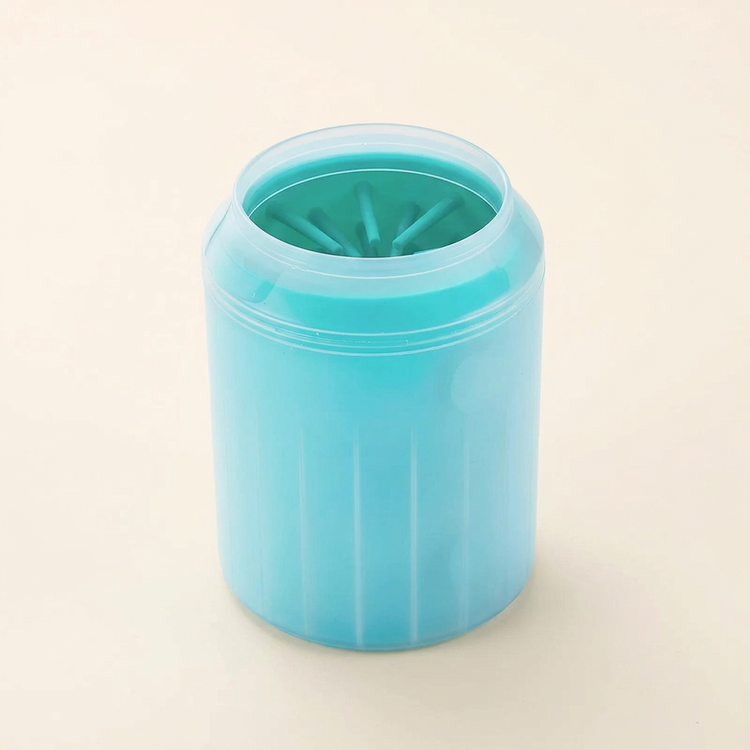 Turquoise dog paw cleaning cup with flexible inner bristles on a cream background